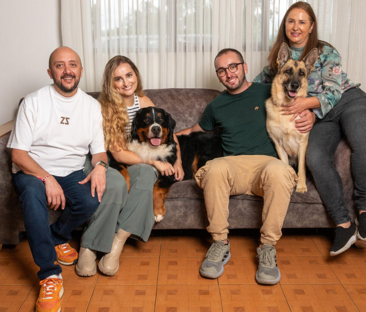 An extended family at home with a Bernese mountain dog and German shepherd